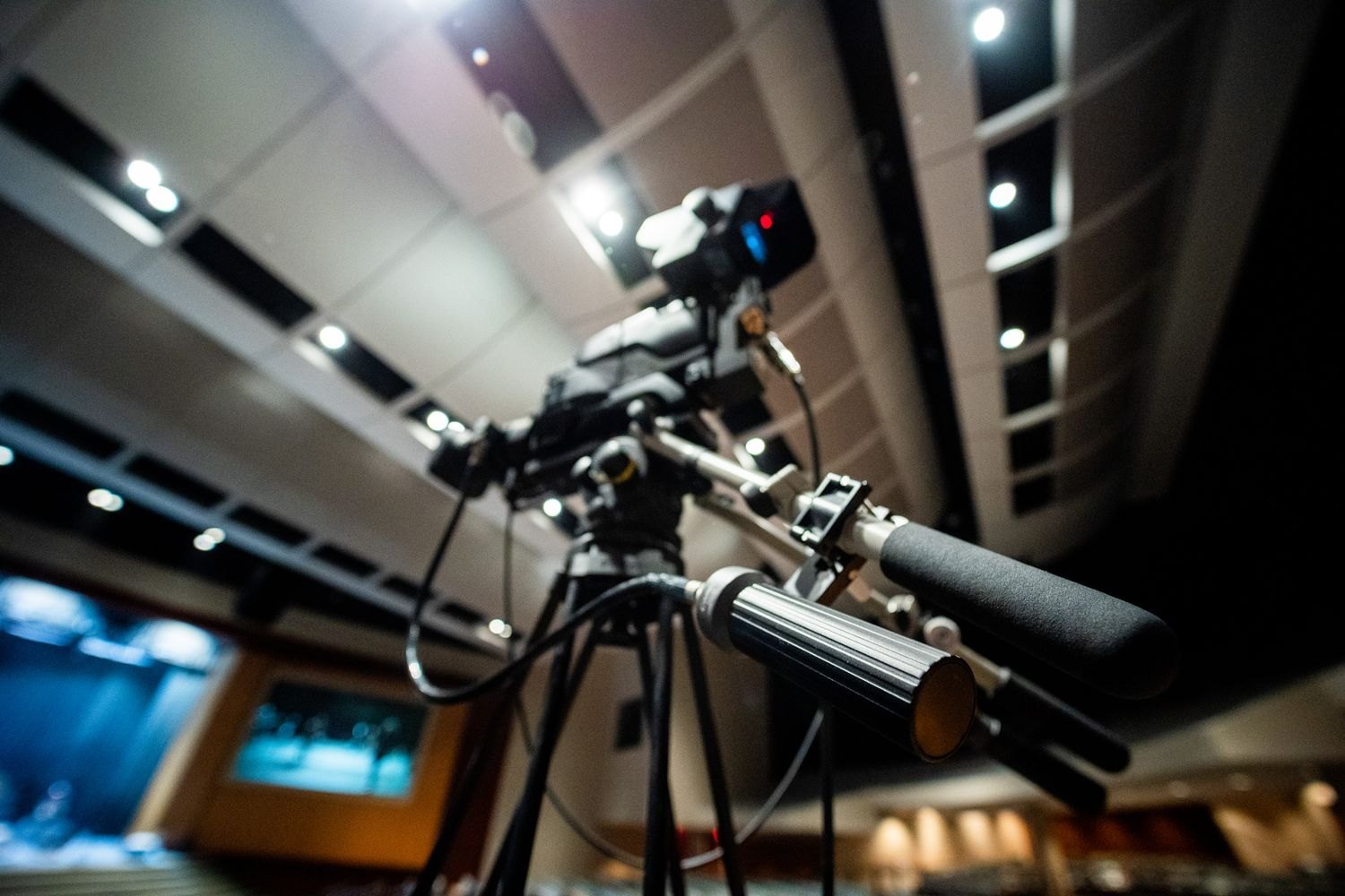 A video camera mounted on a tripod in a studio.