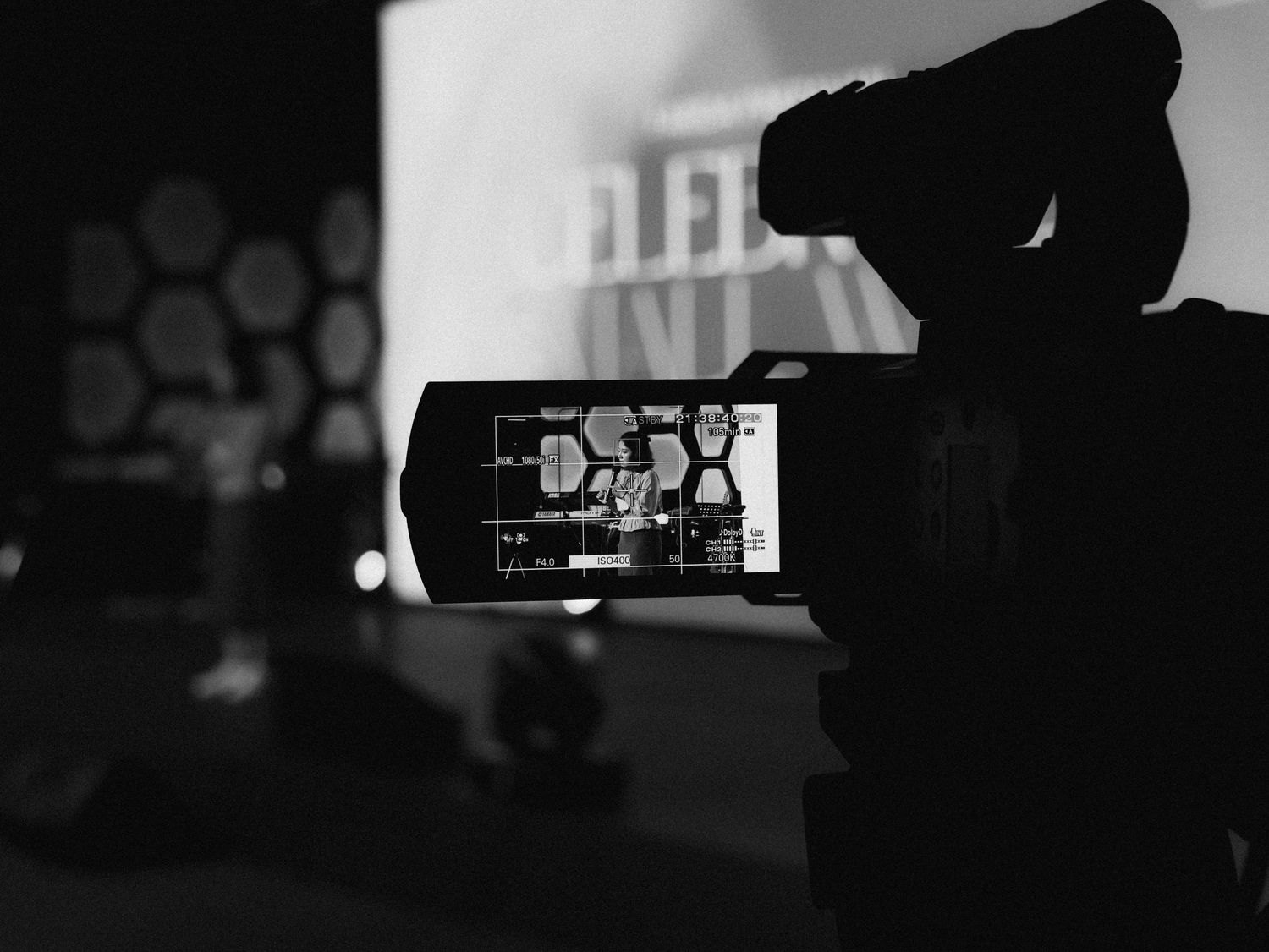 A camera recording a presentation on a stage.