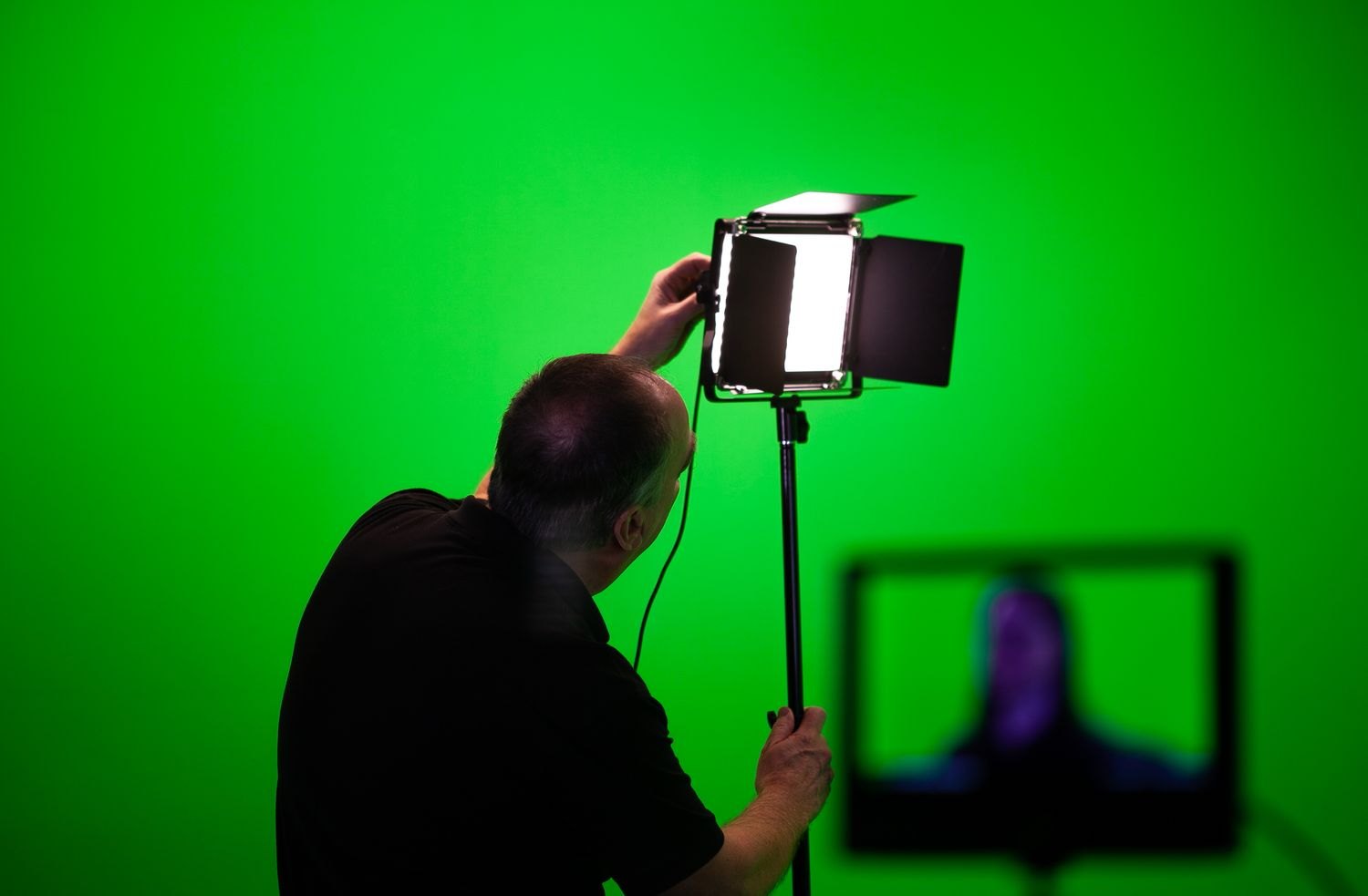 A light being adjusted in front of a green studio background.