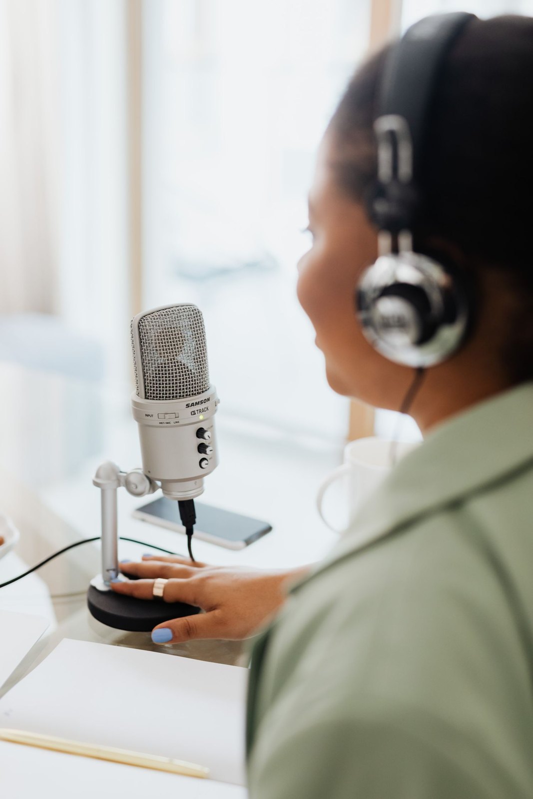 A speaker wearing headphones while recording with a microphone.