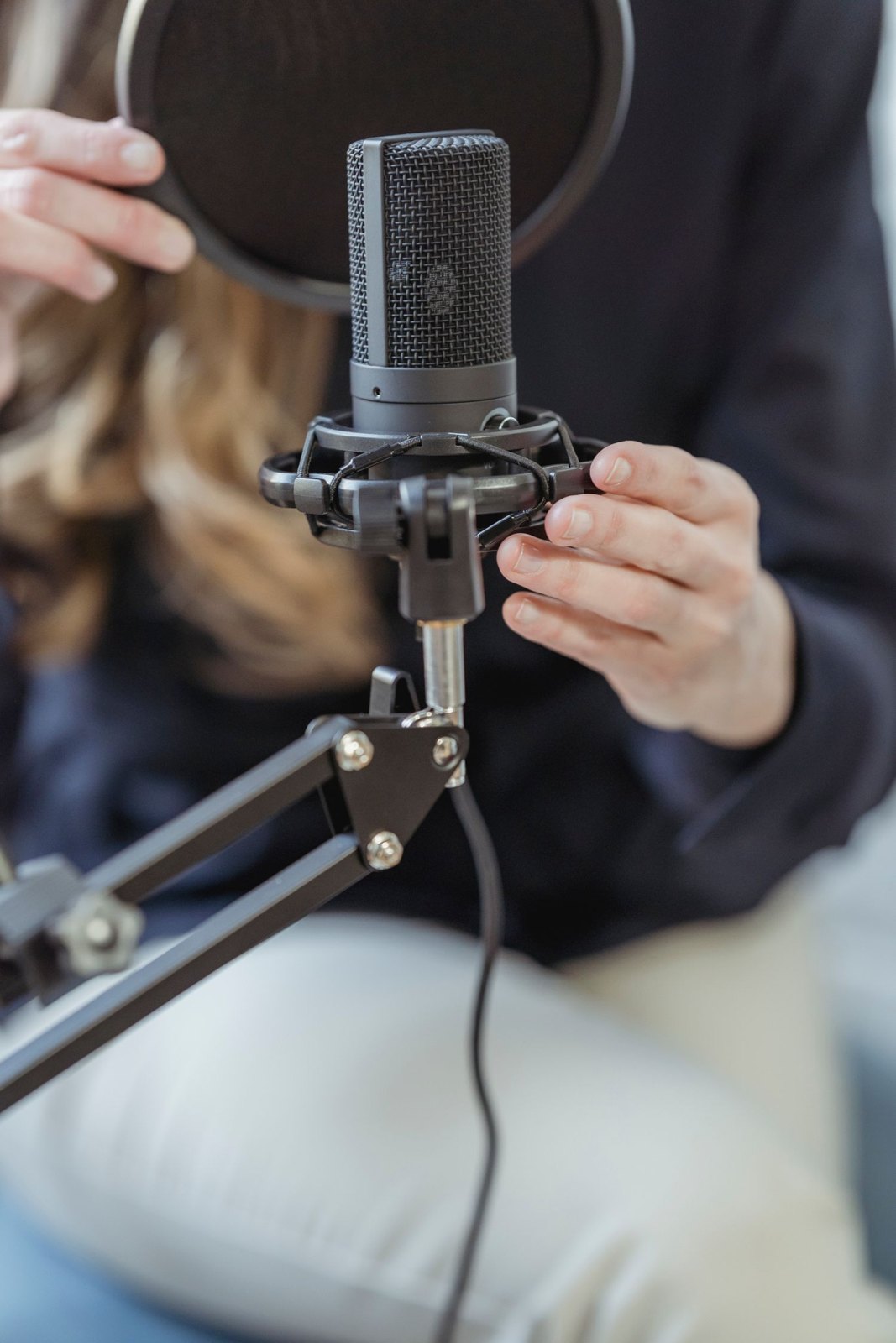Hands adjusting a microphone and its mount.